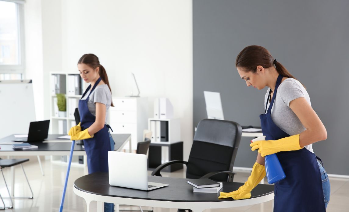 Young man cleaning window in office